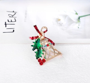 Detailed view of a gold Christmas bell brooch with red bow and colorful rhinestones