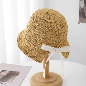 Straw sun hat with white lace bow and back slit design on wooden display stand