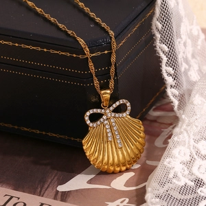 Detailed view of 18K gold plated shell pendant with bow on luxury gift box with lace