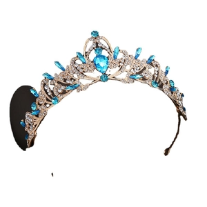 Corona barocca dorata con cristalli blu e strass brillanti su uno sfondo bianco
