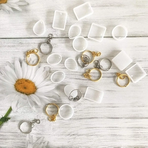 DIY Harz-Schmuckset mit geometrischen Anhängern und Metallringen auf weißem Holzboden