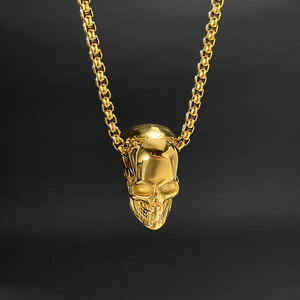 Macro shot of gold skull pendant with vintage texture on a stainless steel box chain