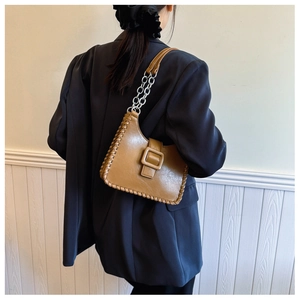 Detail of khaki leather underarm bag with woven edge trim and silver chain strap