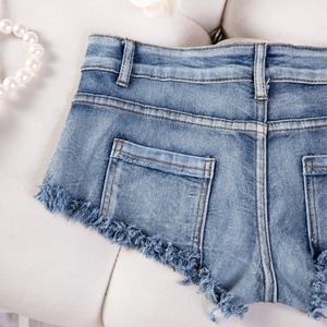 Dettaglio ravvicinato di pantaloncini in denim blu con bordi sfrangiati e tasche posteriori