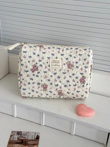 Detailed macro view of quilted makeup bag with purple floral print and teddy bear patterns