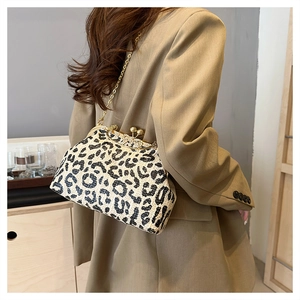 Detail of leopard print sequin clutch with gold chain strap on a model with blazer