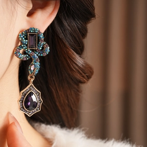 Gros plan de boucles d'oreilles vintage avec pierres bleues, vertes et violettes sur un mannequin