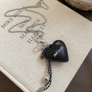 Close-up of black leather heart pendant with silver bow detail and metallic bead chain