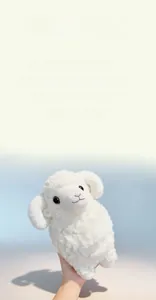 Close-up of white plush lamb toy featuring curly fleece texture and spiral horns