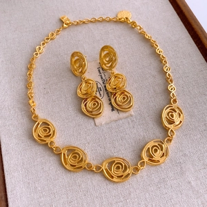 Golden floral jewelry set featuring rose design necklace and earrings on a rustic background