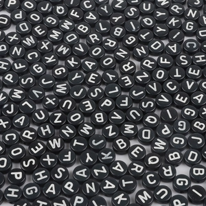 Macro shot of black acrylic flat beads with white uppercase letters for jewelry DIY