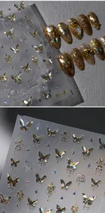 Close-up of laser holographic butterfly nail stickers with gold star patterns and cursive text