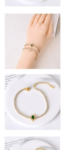 Detailed close-up of a gold-plated tennis bracelet with a pear-cut emerald and lobster clasp