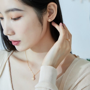 Detailed view of elegant gold jewelry set with opal stones on a model's ear, finger and neck