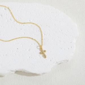 Close-up of 14K gold plated cross pendant with sparkling cubic zirconia on stone base