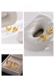 Detailed view of gold triple-layered C-shaped geometric earrings on a stone base