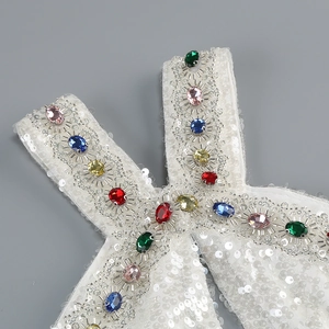 Detail of sequins halter neck dress featuring colorful rhinestones on a white fabric base
