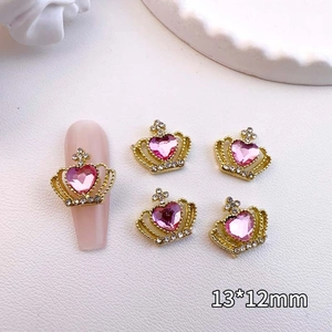 Detailed close-up of 13x12mm gold crown nail art charm with a pink heart gemstone