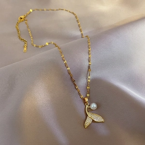 Elegant gold mermaid tail pearl necklace with sparkling micro-pave zircons on silk fabric