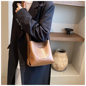 Brown leather bucket bag close-up showing fine texture and branded Macgnee detail