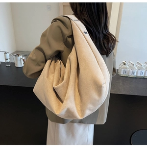 Detailed view of a beige oversized tote bag in brushed texture worn by a model in a studio
