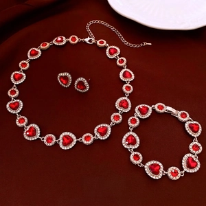 Parure de bijoux coeur dorée avec pierres rouges et cristaux sur fond en velours