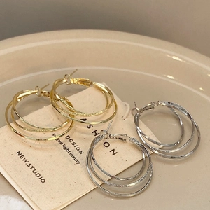 Three-layer interlocking hoop earrings in gold and silver finish with textured details