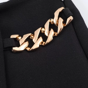 Detailaufnahme einer schwarzen Shorts mit einer polierten goldenen Metallkette