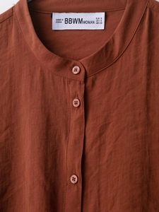 Detail view of the rust brown shirt stand collar with fine linen texture and resin buttons
