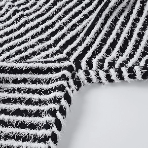 Détail macro du pantalon en maille rayée avec texture à franges et coutures précises