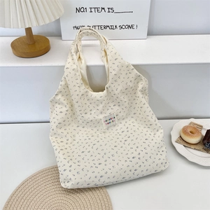 Detailed close-up of corduroy tote bag with blue floral pattern and brand label