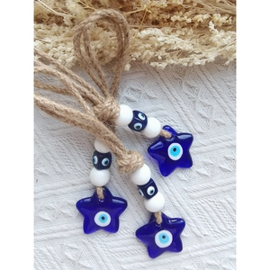 Dettaglio di ciondoli Evil Eye fatti a mano con corda di iuta e stelle di vetro blu