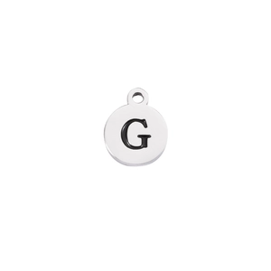 Macro shot of silver stainless steel round pendant with engraved black letter G