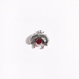 Detailed close-up of a 3D silver ladybug pendant with a red gemstone center on white