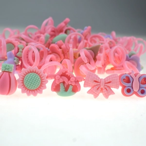 Close-up of pink plastic kids rings featuring sunflower, butterfly and bowknot shapes