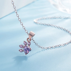 Macro detail of rose gold paw pendant featuring a purple heart stone and dainty chain