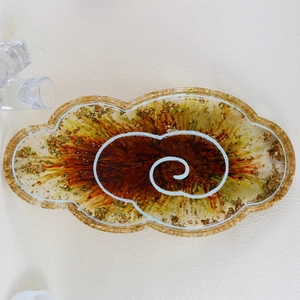Top view of cloud-shaped resin tray with spiral marble texture and gold foil flakes