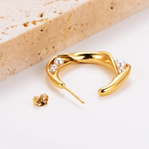 French retro style golden twisted C-shape earrings with pearls on white background