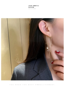 On-model view of long gold tassel star earrings with shimmering metallic chains