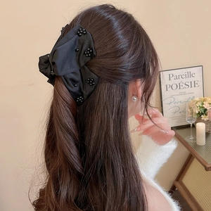 Detail of elegant black satin bow hair claw with beads worn by a female model