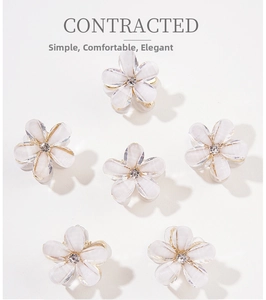 Macro detail of six crystal flower hair clips with iridescent petals and gold metal base