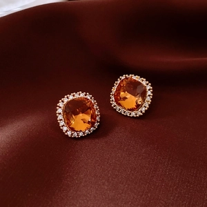 Détail de boucles d'oreilles carrées ambrées avec plaquage or 18 carats sur soie