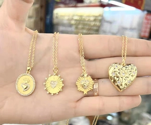 Dettaglio di quattro diversi ciondoli a cuore placcati oro per la creazione di gioielli fai da te