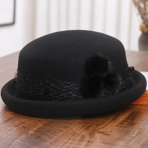 Detail of vintage wool cloche hat with elegant mesh veil and three decorative pom-poms