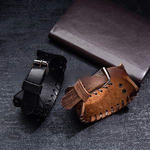 Détail de bracelets en cuir noir et marron avec coutures décoratives et boucle en métal