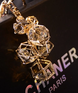 Detail of a geometric gold prism keychain with clear multifaceted crystal on black