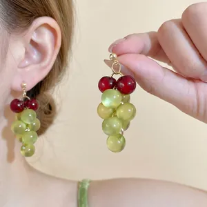 Macro shot of sweet grape drop earrings with green resin beads and golden metal finish