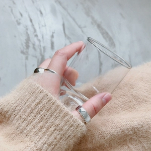 Detailed view of polished S925 sterling silver minimalist rings on a hand holding a glass