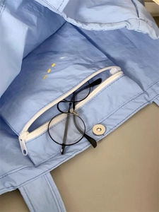 Detail of light blue nylon bag showing zipper inner pocket and silver magnetic closure