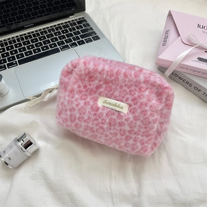 Close-up of pink leopard faux fur cosmetic bag with metal logo and ribbon detail